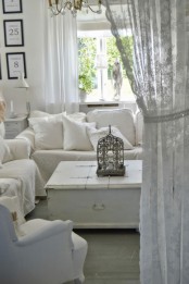 a neutral vintage living room with white sofas, a white coffee table, a chic chandelier and a lantern and a gallery wall