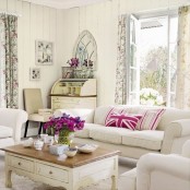 a neutral vintage meets shabby chic living room with several sofas and chairs, a low coffee table, a small bureau in the corner and an upholstered chair plus floral curtains