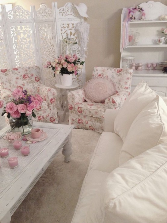 a neutral and chic living room with a white sofa, floral chairs, a low coffee table, pink pillows and blankets and pink blooms in vases