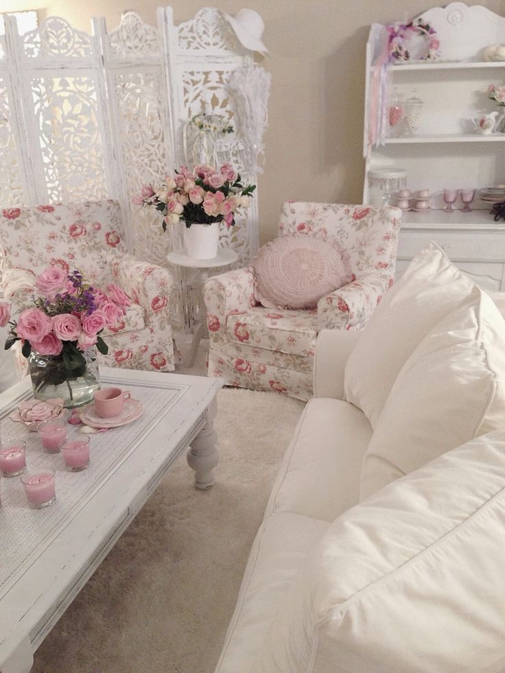 a neutral and chic living room with a white sofa, floral chairs, a low coffee table, pink pillows and blankets and pink blooms in vases