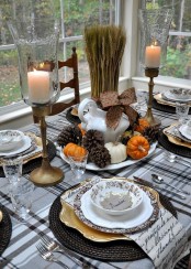 a rustic Thanksgiving table setting with a plaid tablecloth, woven placemats, candles, wheat, pinecones, pumpkins, elegant porcelain is amazing