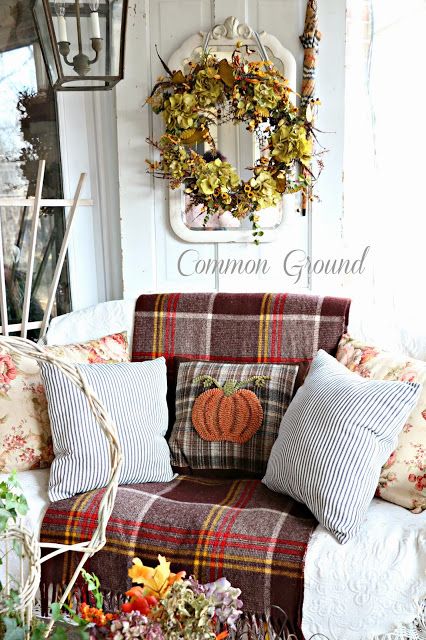 a white chair with a dark plaid blanket, striped and plaid pillows, floral pillows is a lovely idea for fall and Thanksgiving