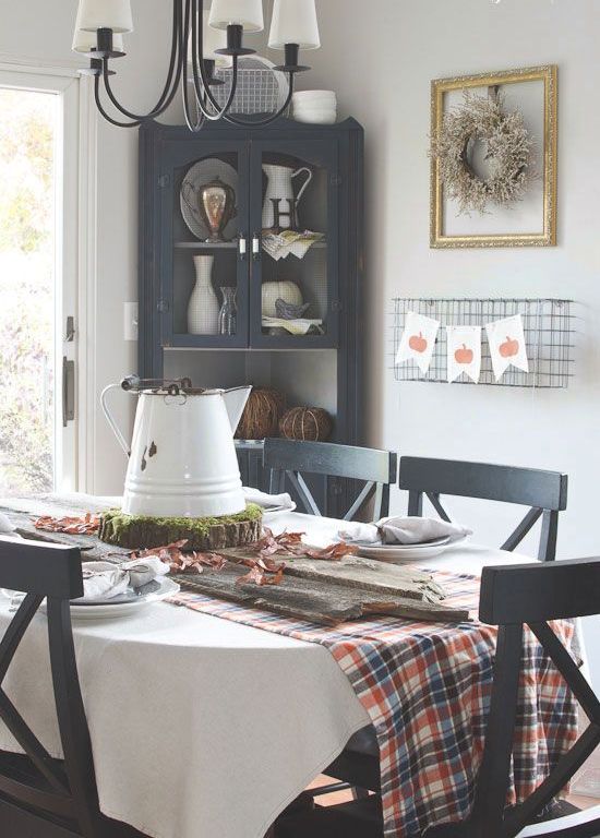 a rustic Thanksgiving tablescape with a plaid runner, a wood slice with a kettle, neutral linens and plates is simple and cute