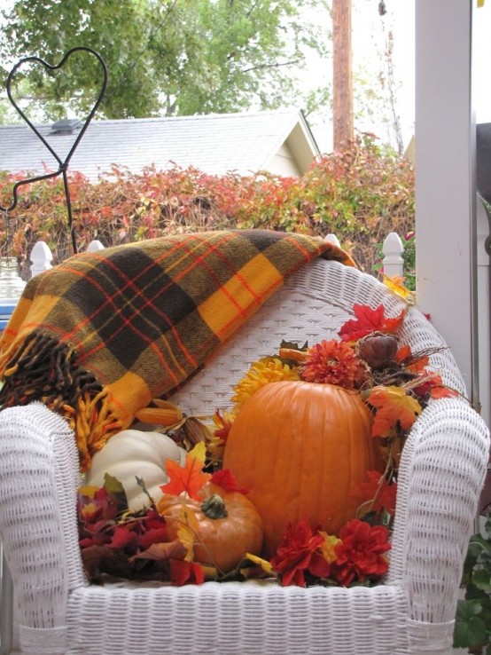 a white wicker chair, pumpkins and leaves plus a plaid blanket is a lovely outdoor or porch decoration you can make yourself