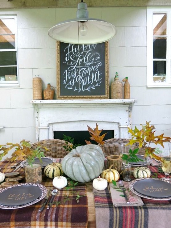 a rustic Thanksgiving tablescape with a plaid tablecloth, patterned chargers and black plates, neutral natural pumpkins and fall leaves