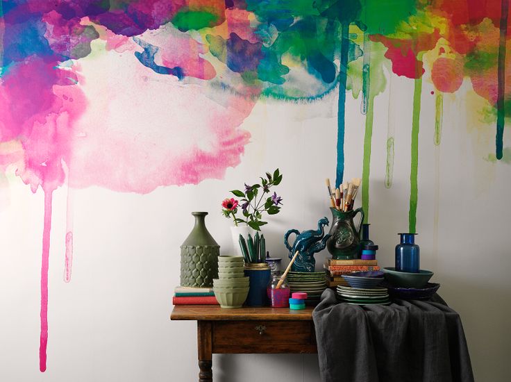 a super bold watercolor accent wall, a table with jewel tone vases and bright blooms that match the watercolors on the wall