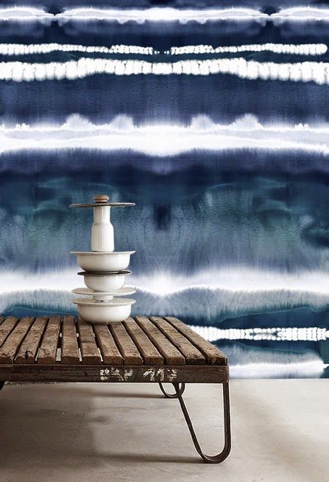 a seaside space with a navy and white watercolor wall, a stained bench and a stack of dishes and bowls is a cool idea
