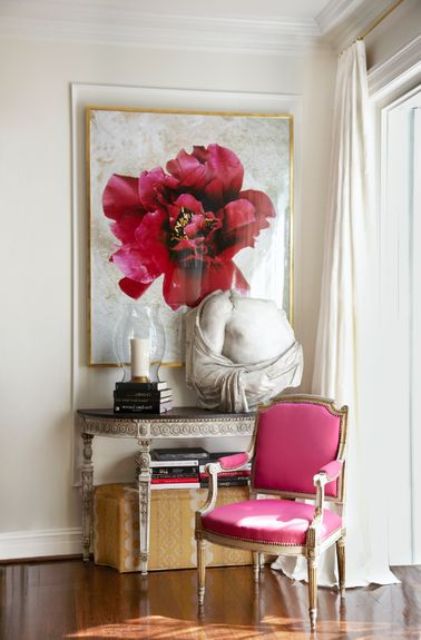 a stylish nook with an oversized pink flower print, a refined console table, a pink antique chair and some beautiful vintage decor