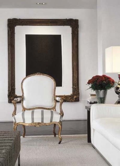 a chic neutral living room with a statement artwork, a creamy sofa, a creamy antique chaira woven bench and a neutral rug