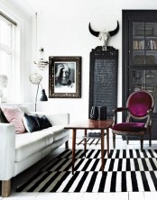 a Scandinavian living room with a white sofa, a stained coffee table, an antique purple chair as a color accent and some gorgeous art on the wall
