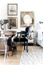 an eclectic bedroom with a stained carved wooden desk, an antique black chair, a gallery wall and a printed rug
