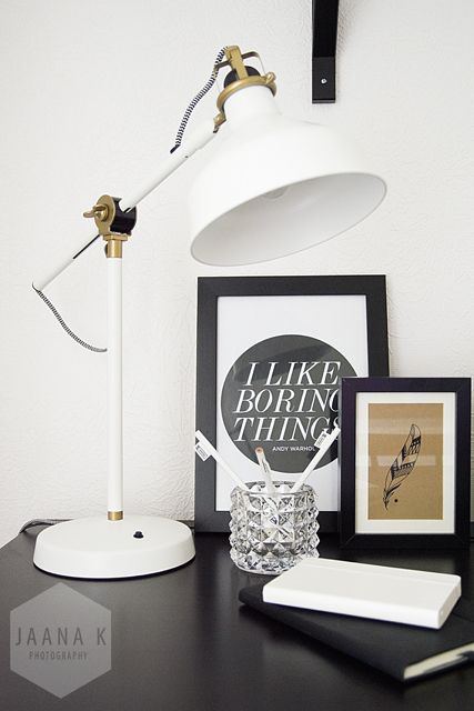 a stylish black and white nook with artworks and a white IKEA Ranarp lamp that brings light and looks elegant