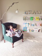a cozy reading nook with a refined chair, ledges with books and a branch with a pendant IKEA Ranarp lamp is very cute