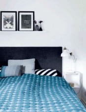 a monochromatic bedroom with white IKEA Ranarp lamps on nightstands and a gallery wall on a ledge