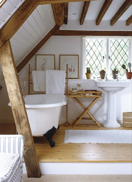 a modern farmhouse bathroom in white, with wooden beams on the walls and ceiling, a tub, vintage sinks