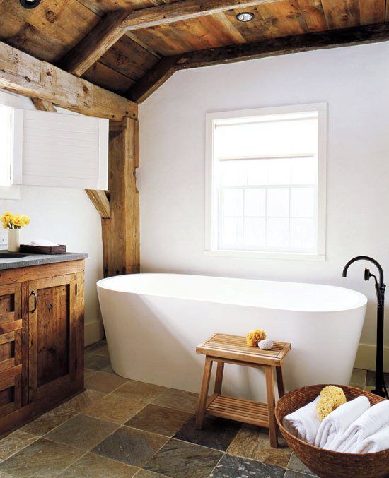 a modern farmhouse bathroom with white walls, a modern tub, a wooden ceiling with beams and a wooden vnaity