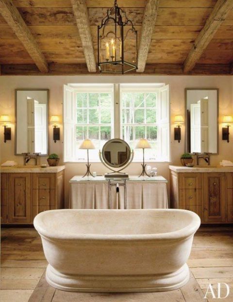 a farmhouse bathroom clad with wood, with a wooden ceiling and beams, two vanities and a vintage tub