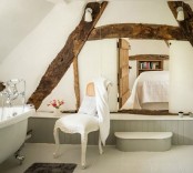 a vintage bathroom with grey paneling, wooden beams on the wall, a vintage tub and vintage fixtures