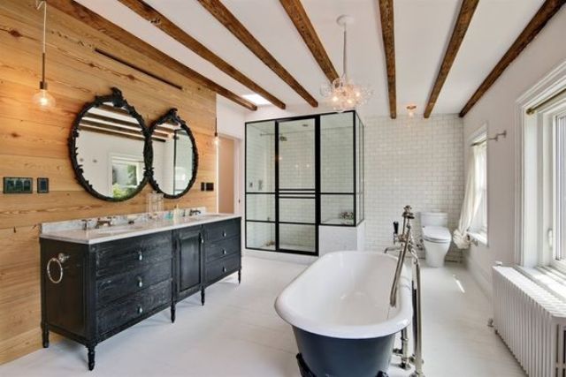 a farmhouse bathroom with wooden beams on the ceiling, a wooden accent wall, a shower clad with glass and a tub