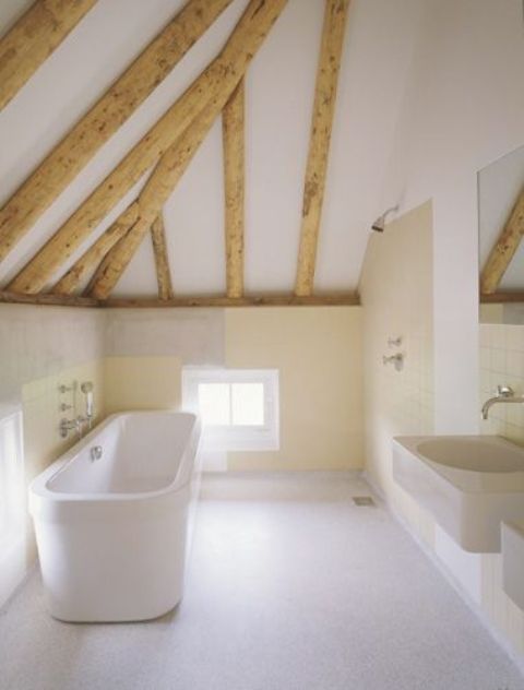 a neutral bathroom with a tile floor, warm colored walls, wooden beams and a free-standing tub