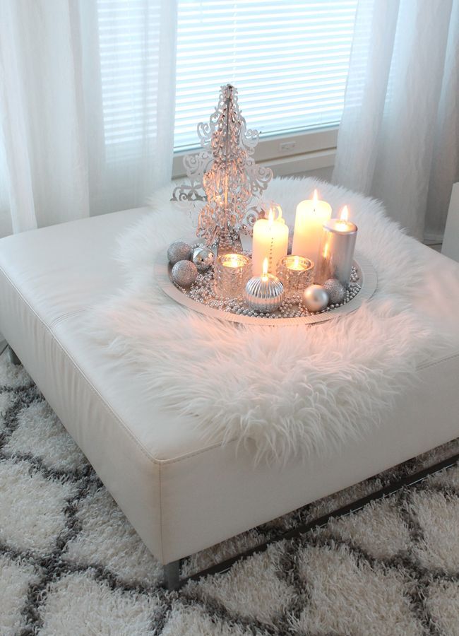a fluffy rug and a white faux fur throw on the ottoman make the living room more welcoming and cozy