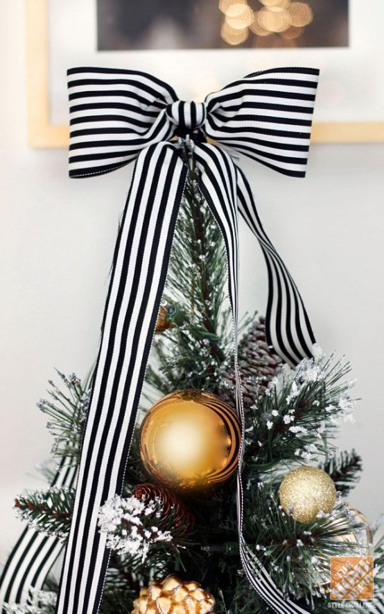 this oversized striped black and white ribbon bow is in perfectl harmony with gold ornaments on the Christmas tree
