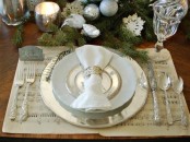shiny Christmas table decor with a shiny charger and cutlery, white and gold edge plate, evergreens with silver ornaments, candleholders and snowflakes