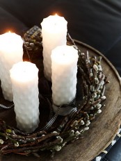 a Nordic spring home decoration of a wood slice, a willow wreath and some white candles for Easter
