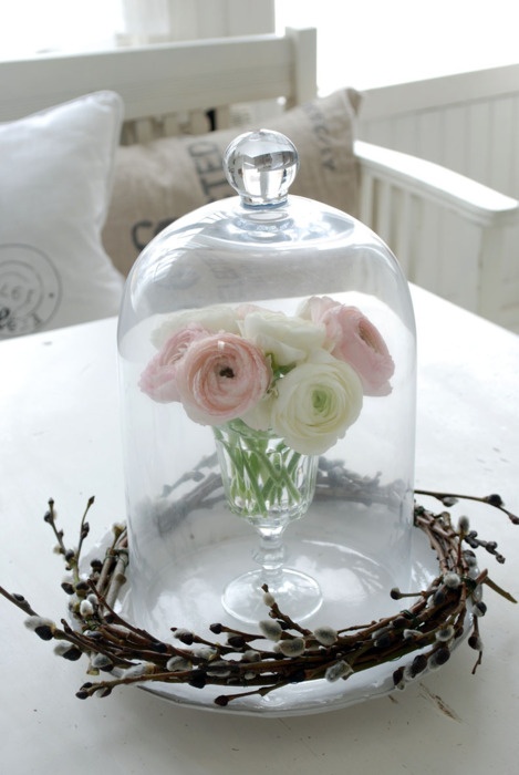 a spring or Easter centerpiece of pink and white blooms in a cloche surrounded with a willow wreath