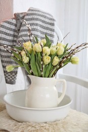 a white jug centerpiece with yellow tulips and willow is ideal for spring or Easter and brings a rustic feel