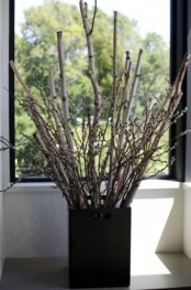 a black square planter with branches and willow that refreshes the natural arrangement for spring and makes it bolder