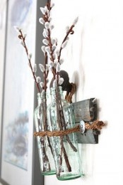 a reclaimed wooden shelf on the wall, glass bottles and willow branches for spring home decor
