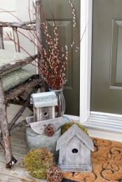 some wooden bird houses, a bucket, a moss and vine ball and some willow in an elegant vase for outdoor or front porch decor