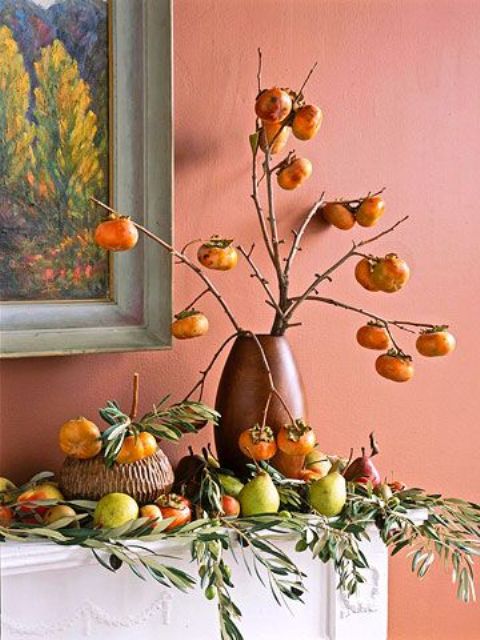 harvest mantel decor with frehs apples, pears and other fruits and a vase with branches with fruits on them