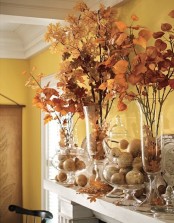tall clear vases with fall leaf arrangements and clear jars with faux pumpkins and pears for a timeless fall mantel