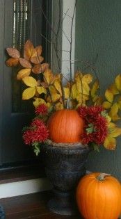a large vintage urn with hay, pumpkins, blooms and fall leaves on branches for decorating your front porch
