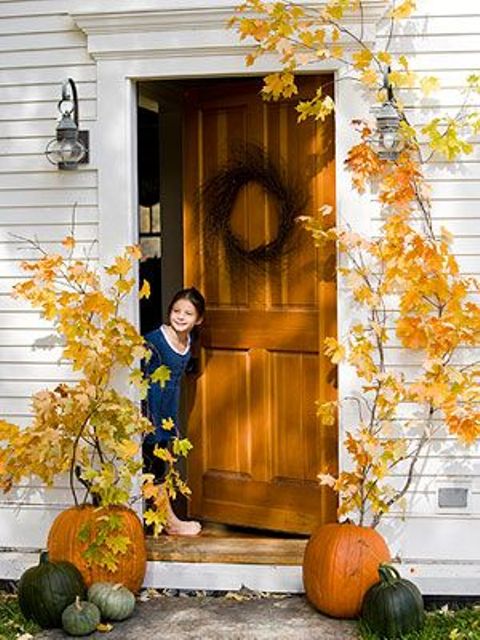 oversized natural pumpkins with tall fall branches inserted into them is a cool outdoor decoration to frame your door