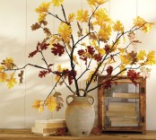 an antique-inspired vase with branches and yellow leaves on them for bold fall decor