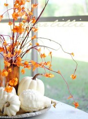 branches with colorful fall blooms and neutral pumpkins make up a cool fall centerpiece or an arrangement for decor