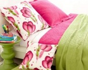 bright bright pink bedding and a side table make the bedroom look bold, bright and fun