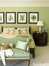a green bedroom with a gallery wall of botanicals and bright bedding and pillows for a spring feel