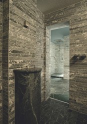 a minimalist bathroom fully clad with tiles that imitate real stone and a stone fre-standing sink