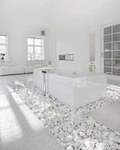a white minimalist bathroom with a whole pile of white stones and a bathtub put on them