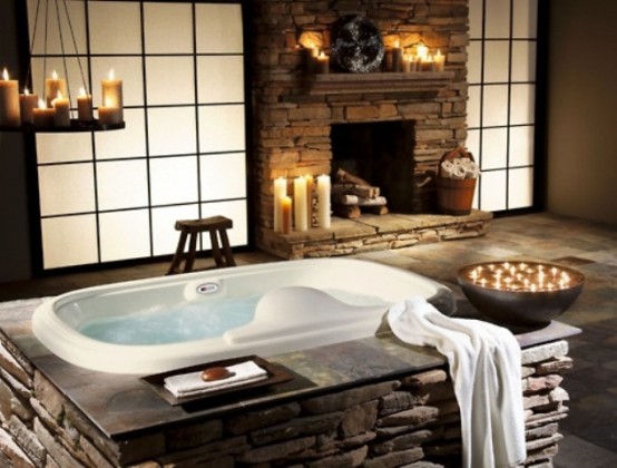 a bathtub and a fireplace clad with decorative stone plus lots of candles that create a mood and an atmosphere