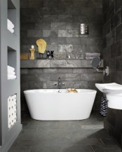 a contemporary bathroom clad with dark stone-like tiles completely to make the space more eye-catchy and chi