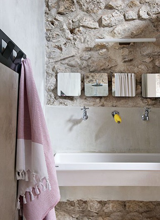 a rough stone wall and a concrete vanity with a built-in sink make up a chic contrasting combo