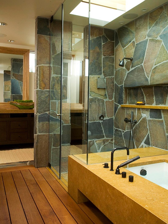 a contemporary bathroom with a touch of rustic chic - a stone wall and stained wooden floors