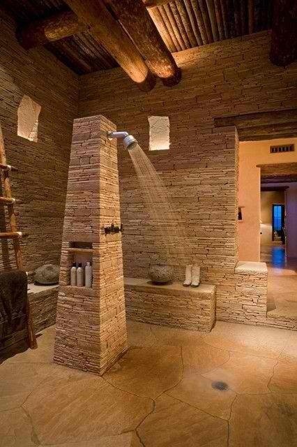 a large neutral bathroom all clad with stone and with some wooden touches looks very welcoming and chic