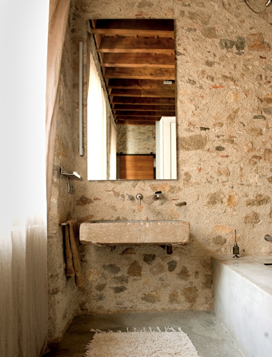 a French farmhouse bathroom with stone walls and a stone sink attached to the wall is very pretty