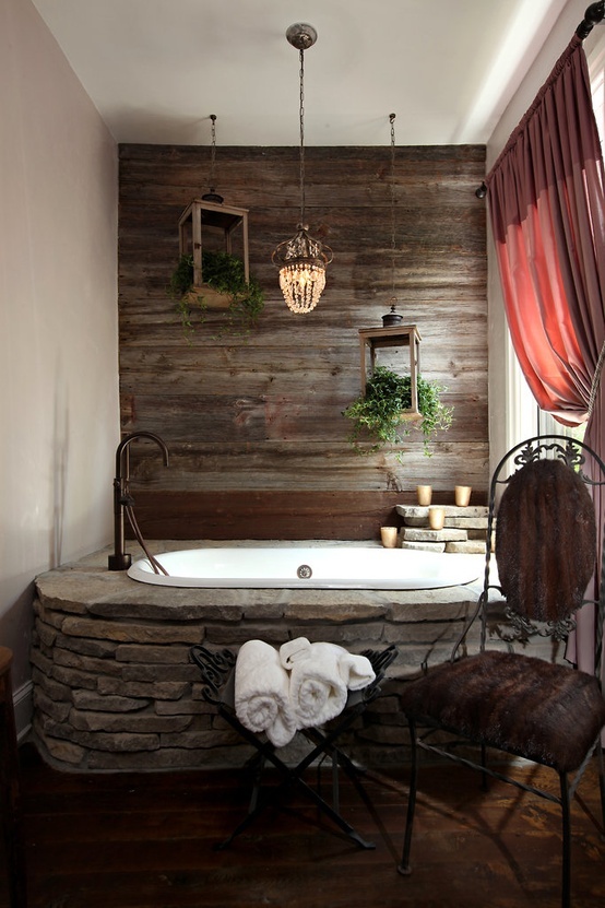 a refined eclectic bathroom with a reclaimed wood wall, a bathtub clad with ston and a burgundy curtain